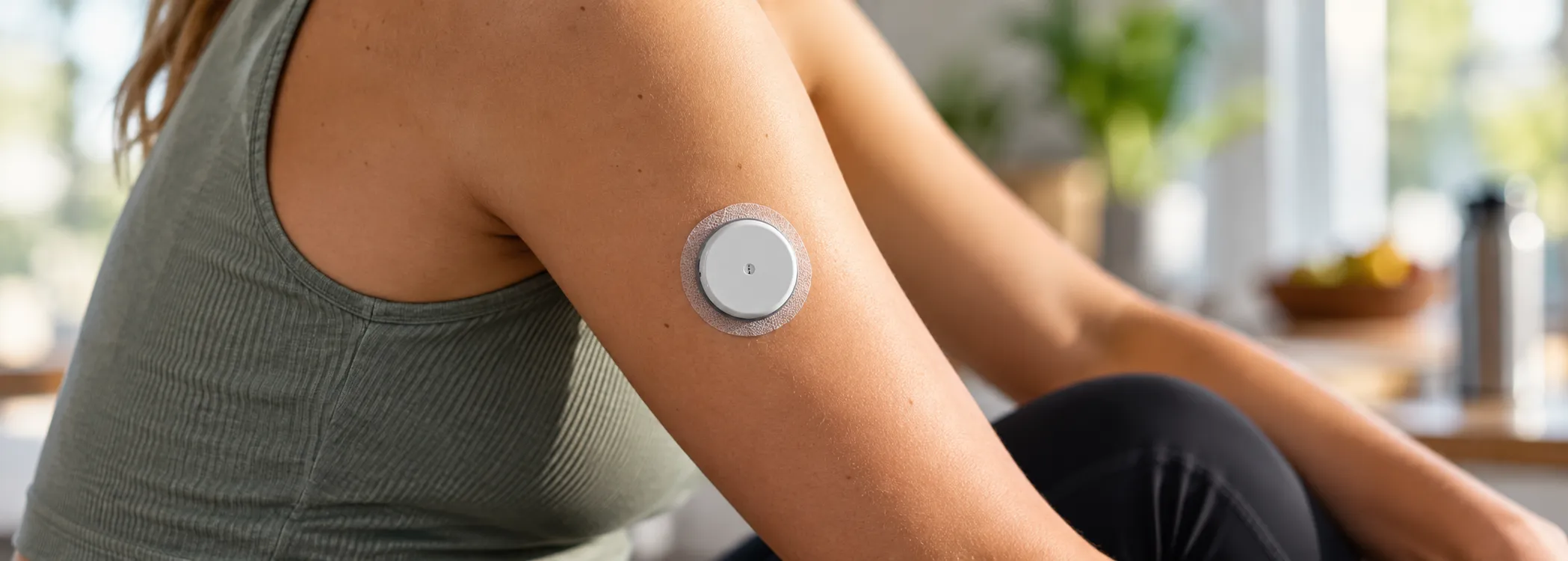Person mit einem Sensor zur kontinuierlichen Glukosemessung am Oberarm